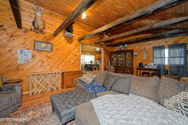 living area with beam ceiling, wood walls, and wood finished floors
