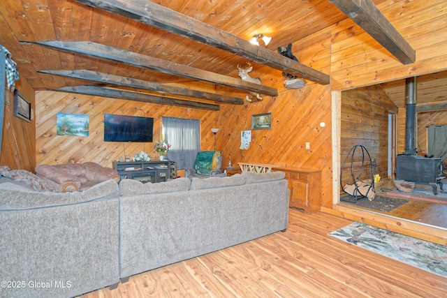 living area with a wood stove, wood finished floors, beam ceiling, wooden walls, and wood ceiling