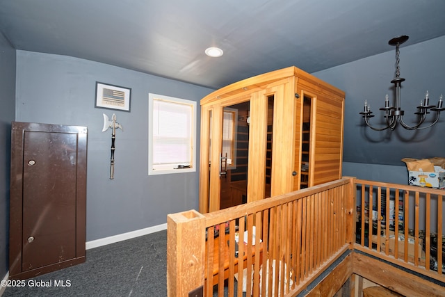 interior space featuring baseboards, carpet, a chandelier, and an upstairs landing