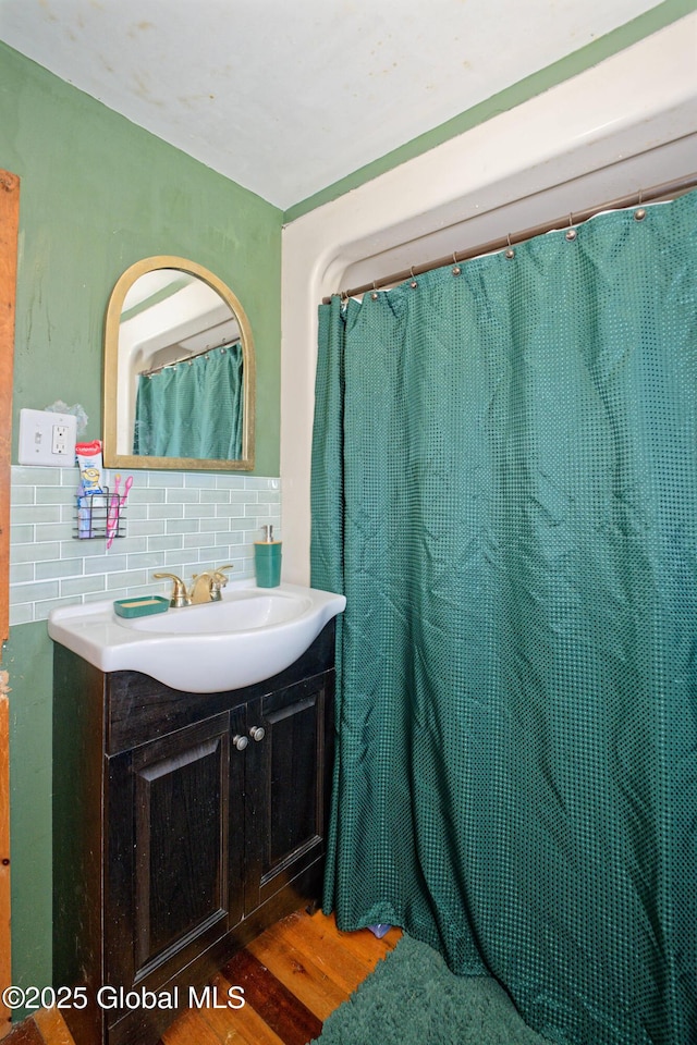 full bathroom featuring vanity, tasteful backsplash, and wood finished floors