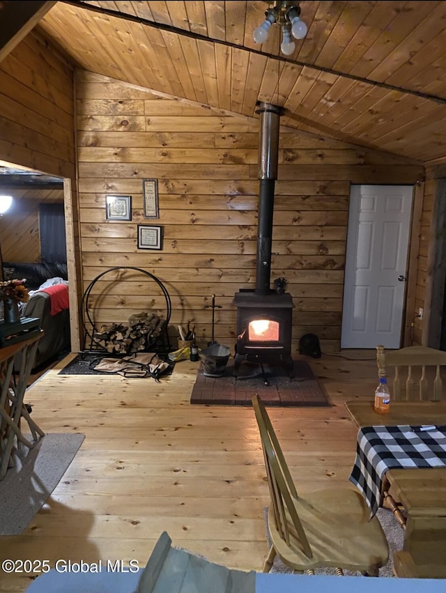 living room with wooden walls, a wood stove, hardwood / wood-style flooring, and lofted ceiling