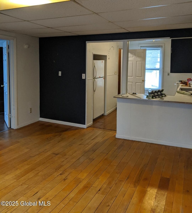 interior space with baseboards, light wood-style flooring, and a paneled ceiling