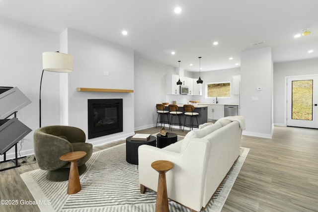 living room with recessed lighting, light wood-style floors, baseboards, and a healthy amount of sunlight
