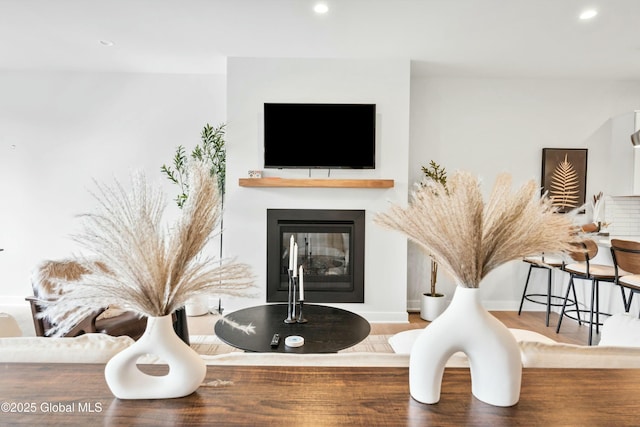interior details with recessed lighting, baseboards, a glass covered fireplace, and wood finished floors
