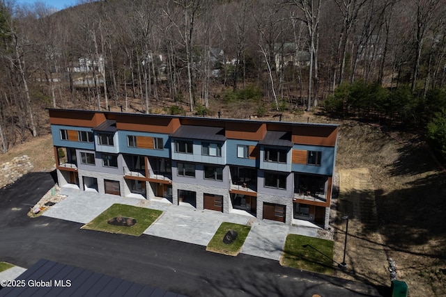 view of front of home featuring a standing seam roof, an attached garage, driveway, and a balcony