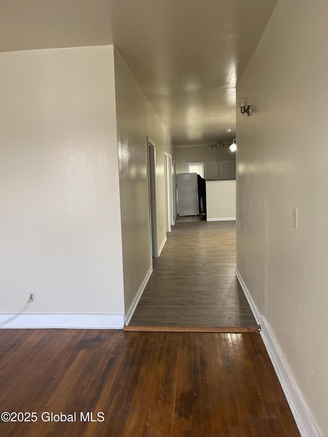 corridor featuring dark wood-style flooring and baseboards
