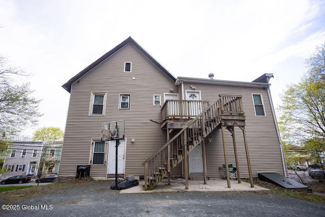 rear view of house featuring stairs and a wooden deck