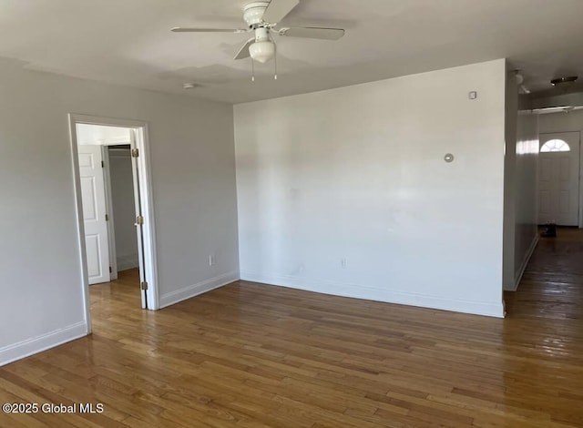empty room with a ceiling fan, baseboards, and wood finished floors