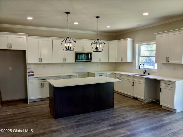 kitchen with hanging light fixtures, tasteful backsplash, a sink, stainless steel microwave, and white cabinetry