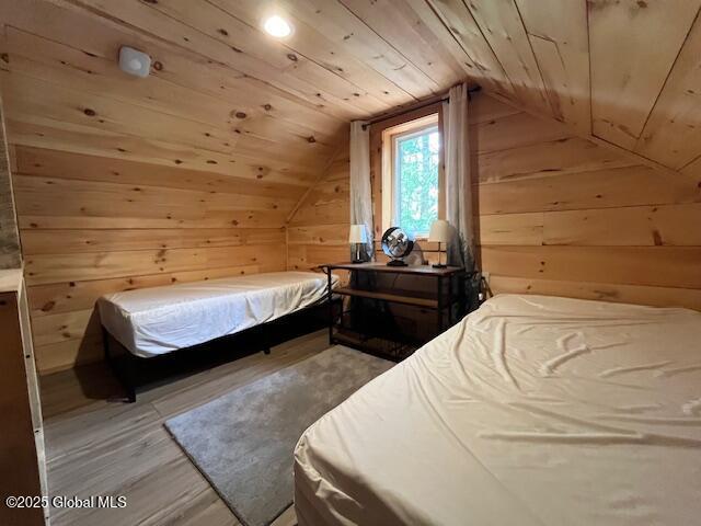 15-17 Pine Rd, Lake Luzerne, NY 12846 - bedroom with wood walls, wood ceiling, vaulted ceiling, and light wood-type flooring