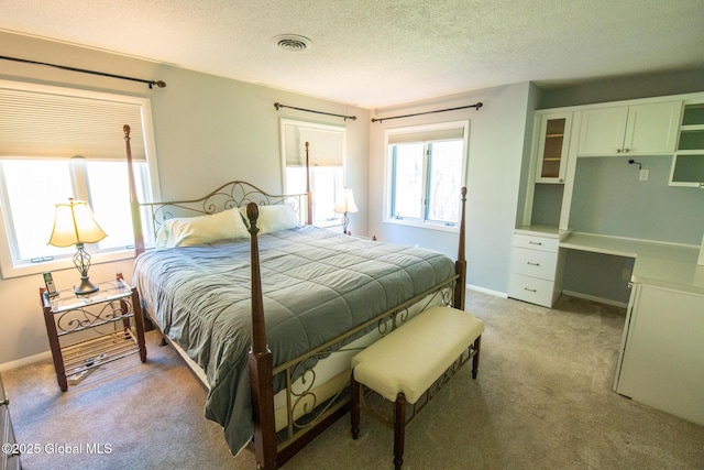 bedroom featuring visible vents, a textured ceiling, baseboards, and light carpet