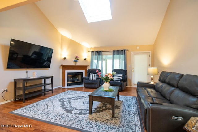 living room featuring a skylight, high vaulted ceiling, a fireplace with flush hearth, and wood finished floors