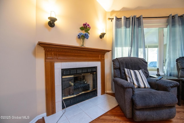 living area featuring a tile fireplace and wood finished floors