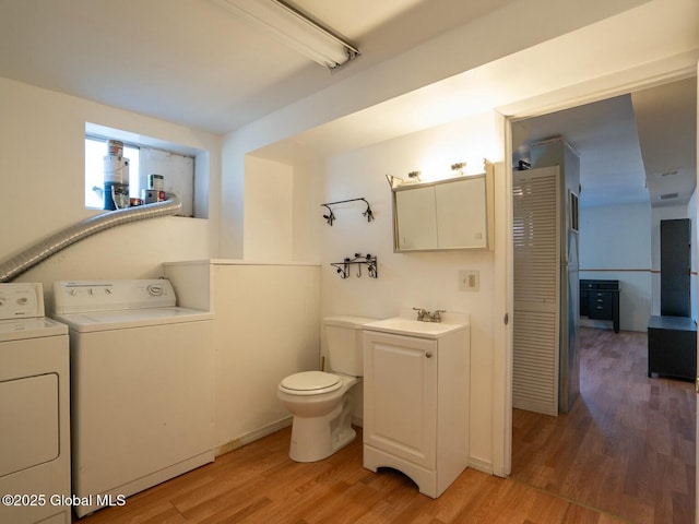 bathroom with separate washer and dryer, vanity, toilet, and wood finished floors