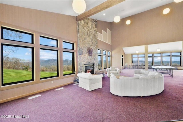 carpeted living area with visible vents, a towering ceiling, beam ceiling, and a fireplace