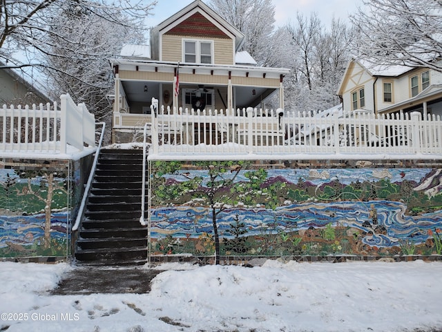 view of front of property with a ceiling fan, fence private yard, and stairway