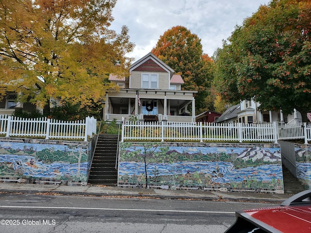 view of front of home featuring stairs, a fenced front yard, and a porch