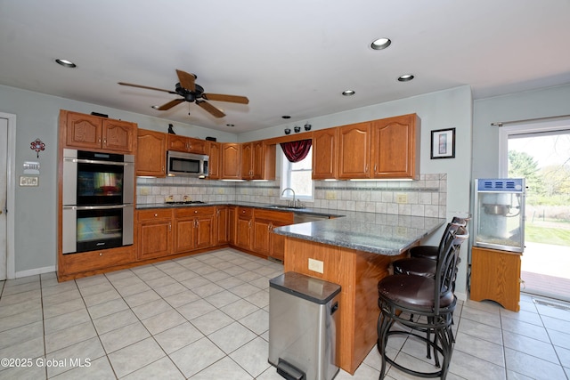 37 Old Hickory Rd, Brunswick, NY 12180 - kitchen featuring a peninsula, decorative backsplash, stainless steel appliances, and brown cabinetry