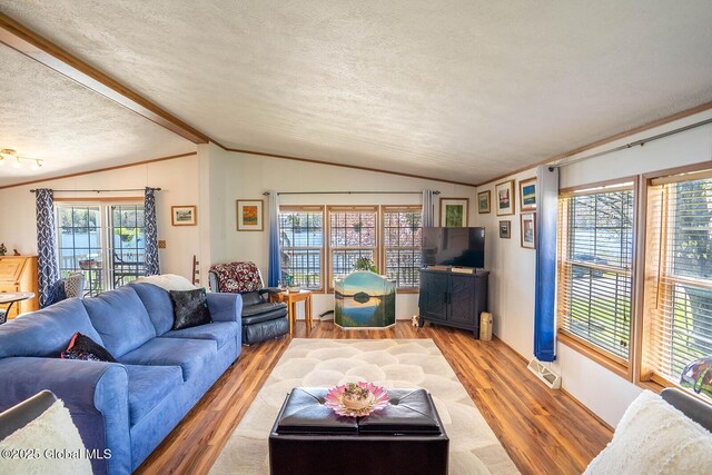 living room with a textured ceiling, vaulted ceiling, ornamental molding, and light wood-style flooring