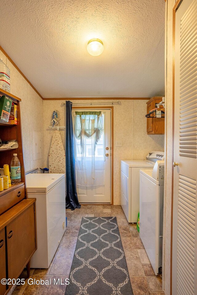 washroom featuring laundry area, ornamental molding, a textured ceiling, and washing machine and clothes dryer