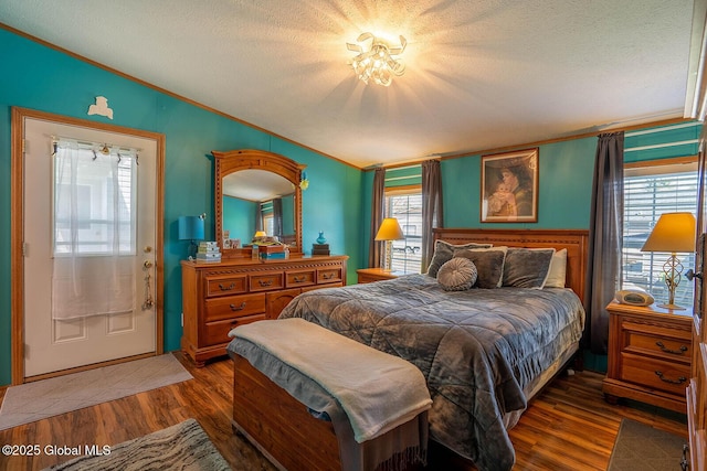 bedroom featuring crown molding, a textured ceiling, wood finished floors, and vaulted ceiling
