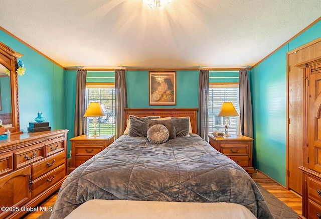 bedroom with crown molding, a textured ceiling, and wood finished floors