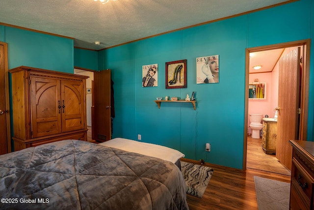 bedroom featuring baseboards, a textured ceiling, wood finished floors, and ensuite bath