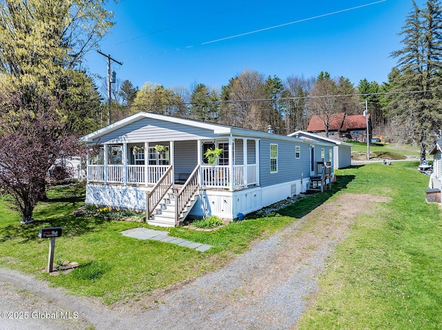 manufactured / mobile home featuring a porch, driveway, and a front yard