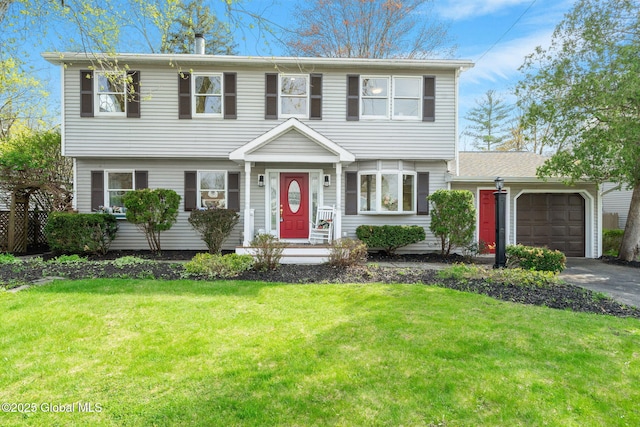 colonial house with concrete driveway, a front yard, and a garage