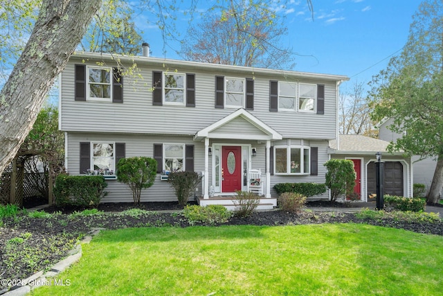 colonial home with an attached garage and a front lawn