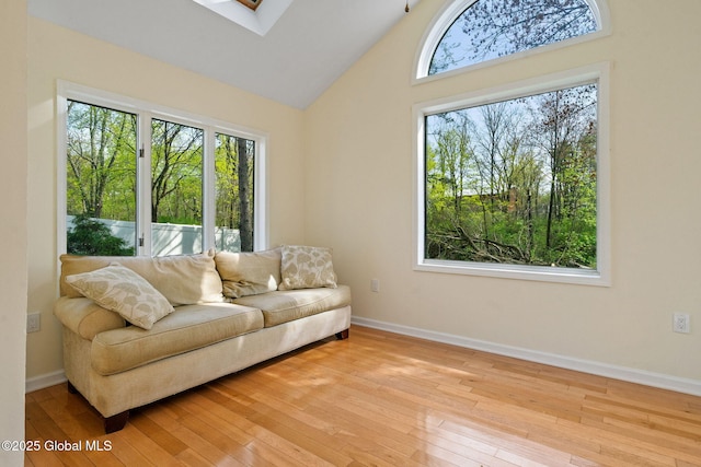living area featuring baseboards, a skylight, and light wood-style flooring