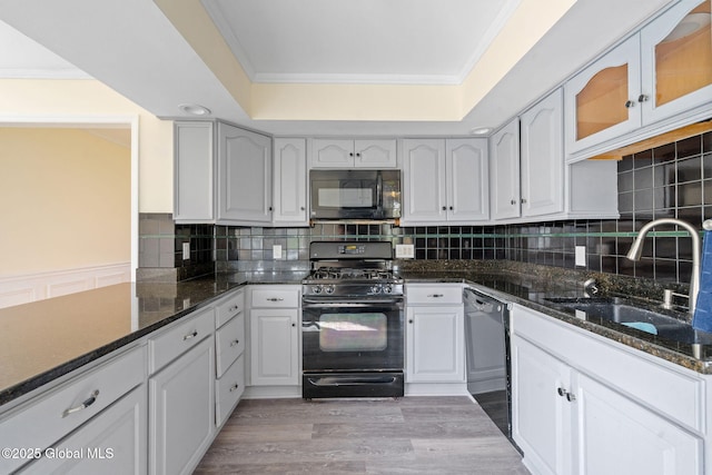 kitchen featuring a sink, crown molding, black appliances, and dark stone countertops