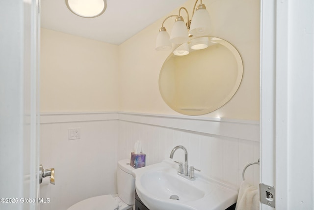 half bathroom with a wainscoted wall, vanity, and toilet