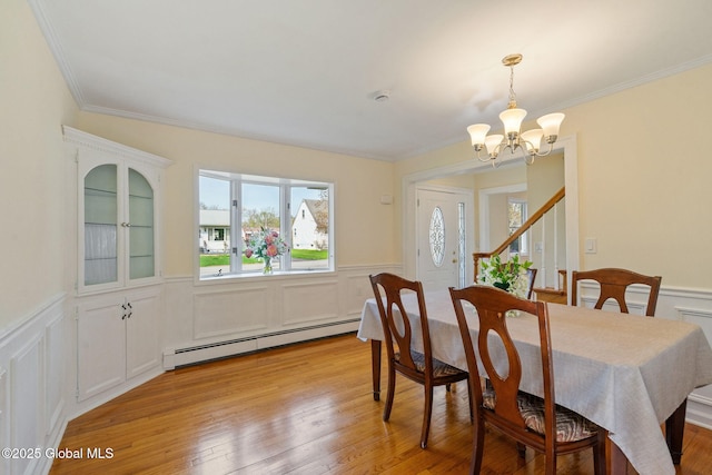 dining space with an inviting chandelier, a baseboard radiator, wainscoting, and a wealth of natural light