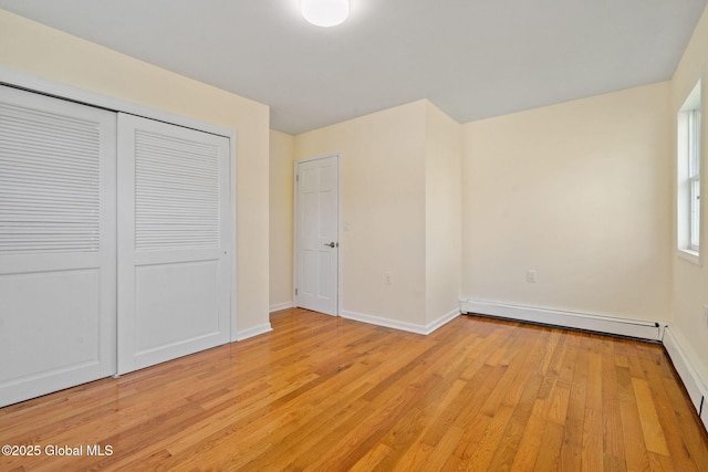 unfurnished bedroom featuring baseboards, a baseboard radiator, a closet, and light wood finished floors