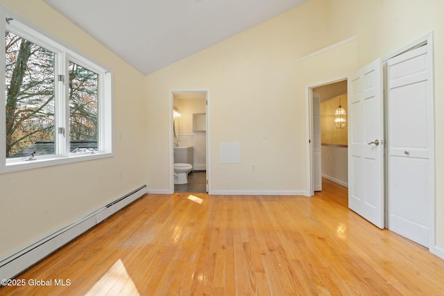 unfurnished bedroom with light wood finished floors, baseboards, ensuite bathroom, a baseboard radiator, and vaulted ceiling