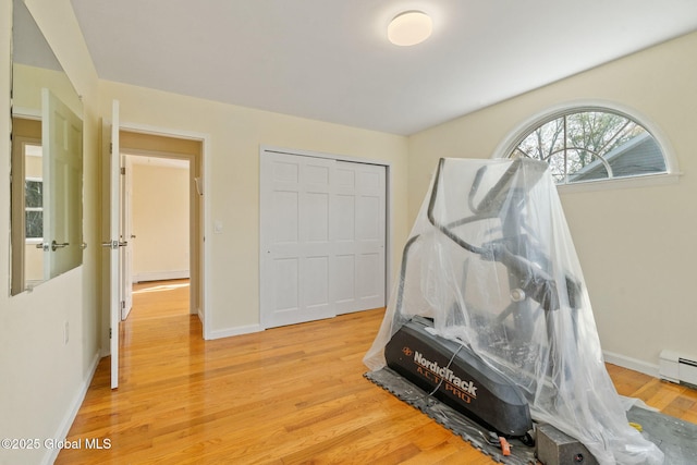 workout area with baseboards and light wood-style flooring