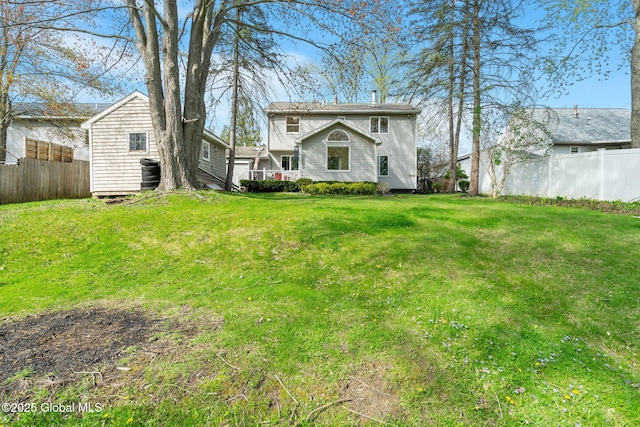 rear view of property with fence and a yard