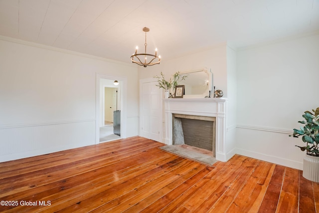 unfurnished living room featuring a chandelier, hardwood / wood-style flooring, a tile fireplace, and ornamental molding