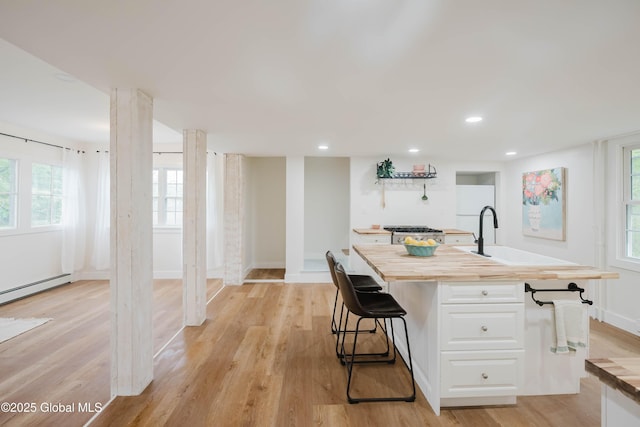 kitchen with wooden counters, white cabinets, light wood-style floors, and recessed lighting