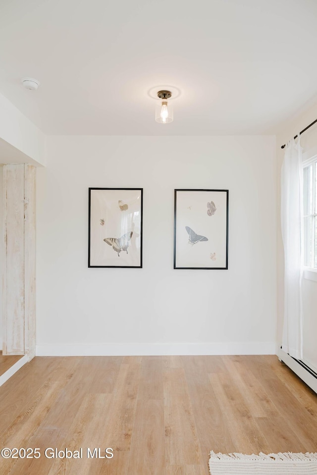 unfurnished room featuring wood finished floors, a smoke detector, and baseboards