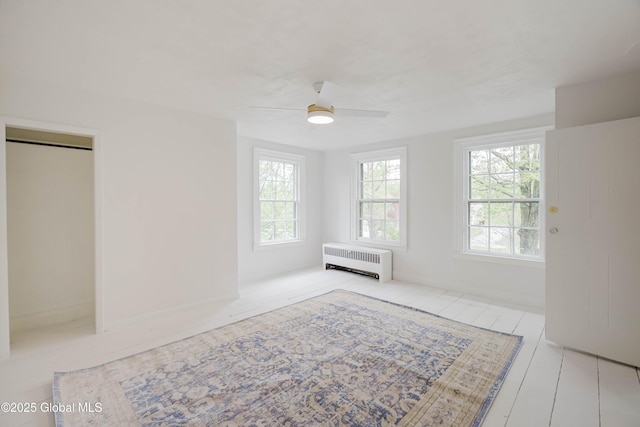 unfurnished bedroom with radiator heating unit and a ceiling fan
