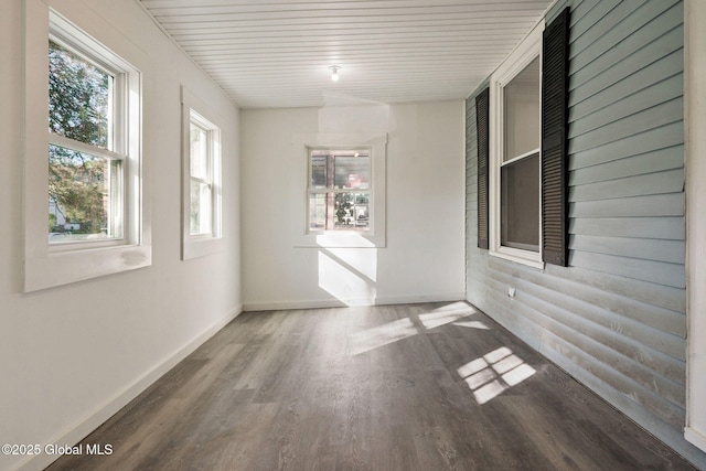 empty room featuring baseboards, wooden ceiling, and wood finished floors