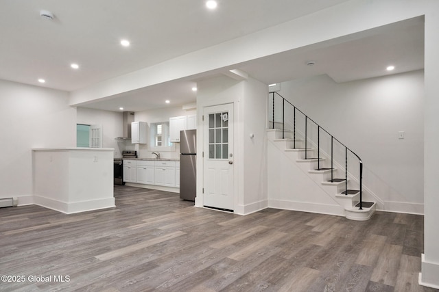 interior space featuring wood finished floors, recessed lighting, white cabinets, a sink, and stainless steel appliances