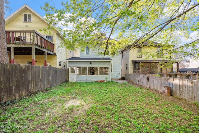 rear view of house with a sunroom, a fenced backyard, and a yard
