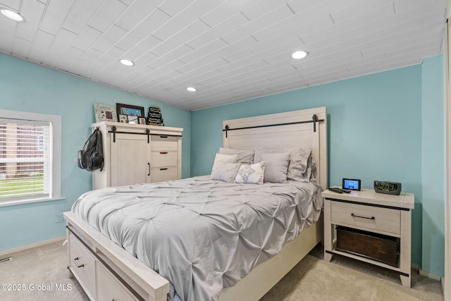 bedroom with baseboards, recessed lighting, a barn door, and light colored carpet