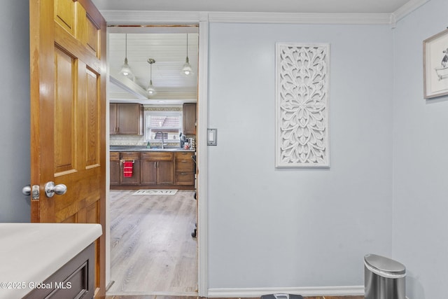 hallway featuring a sink, ornamental molding, and wood finished floors