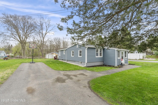view of property exterior with a storage shed, fence, an outdoor structure, and a lawn