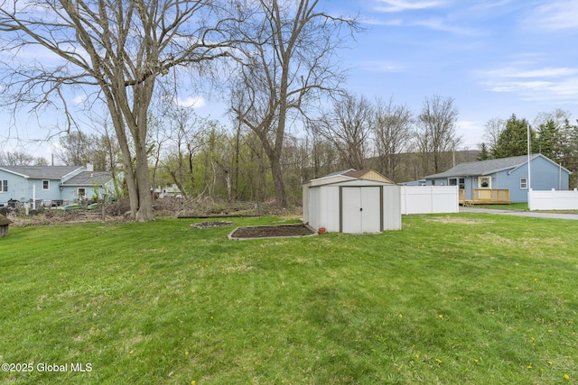 view of yard with an outbuilding, fence, a storage shed, and a wooden deck