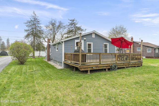 rear view of property featuring a chimney, a yard, and a deck